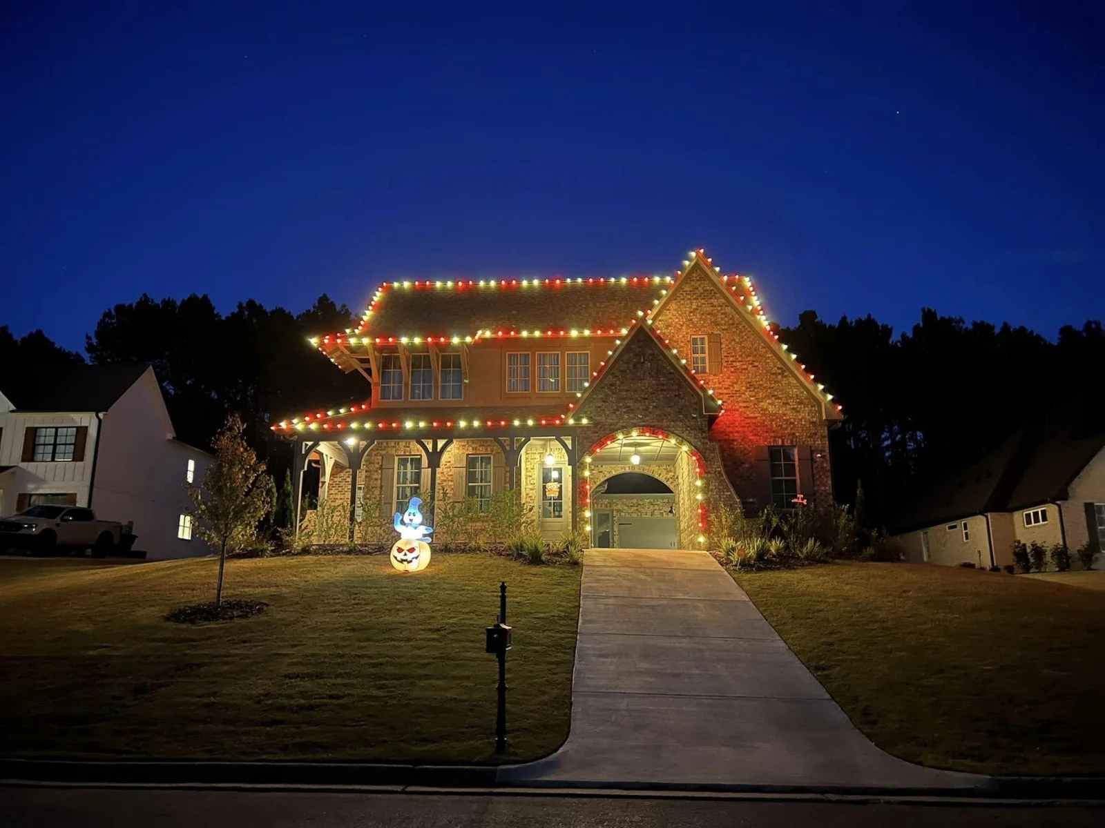 Home lit end to end in red and green bulbs with an inflatable snowman on the lawn